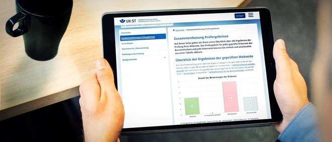 eine Person hält ein Tablett in der Hand, es zeigt eine Webseite mit einem Bericht und Diagramm - zum Bericht 2022 der Überwachungsstelle