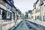 Sanierung einer Straße zwischen historischen Häusern. Straße und Gehwege sind mit vielen Absperrungen voneinander getrennt.