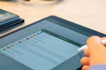 eine Person bedient ein Tablet auf einem Schreibtisch