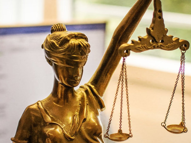 Justitia steht vor einem Monitor, der ein Dokument zeigt