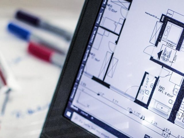 Grundrisse auf einem Laptop und auf dem Schreibtisch