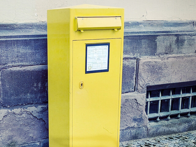 gelber Briefkasten an einer Mauer
