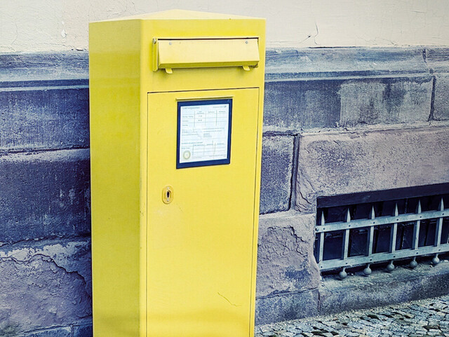 gelber Briefkasten an einer Mauer
