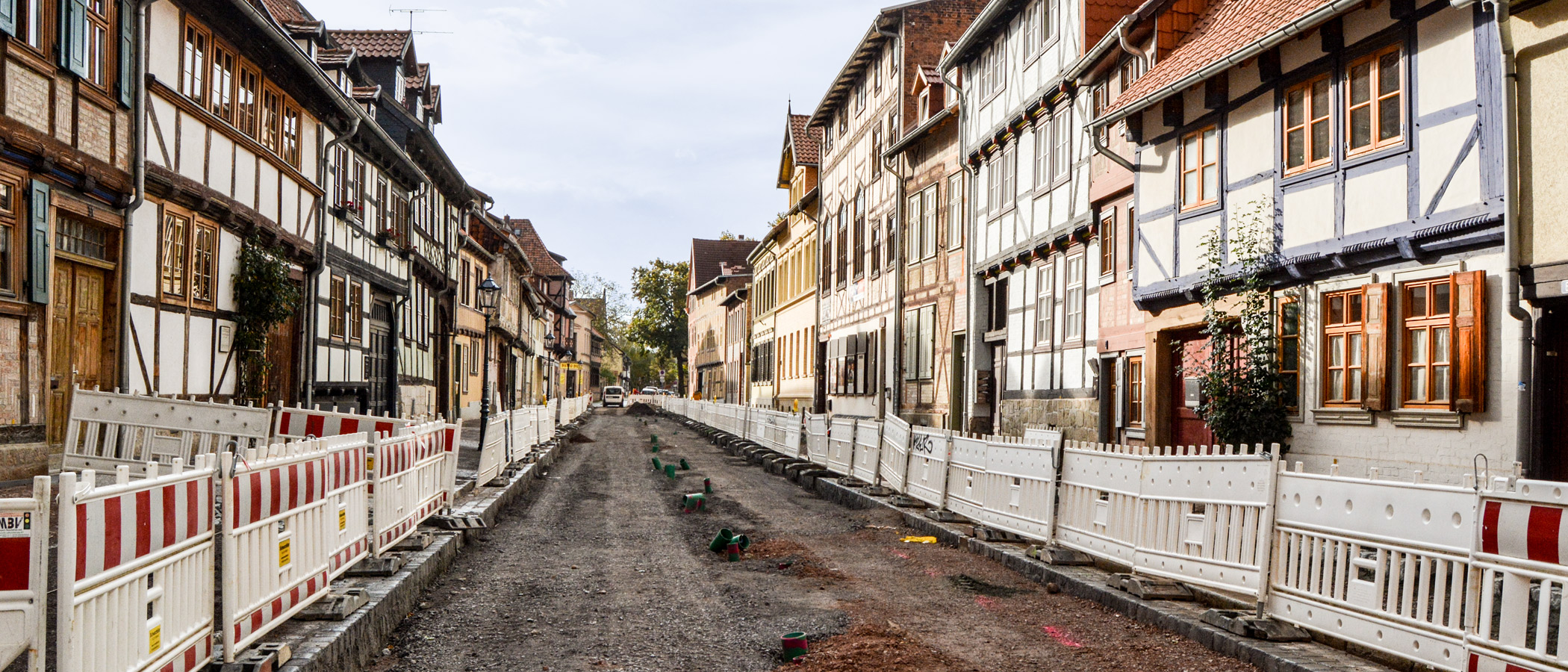 Sanierung einer Straße zwischen historischen Häusern. Straße und Gehwege sind mit vielen Absperrungen voneinander getrennt.