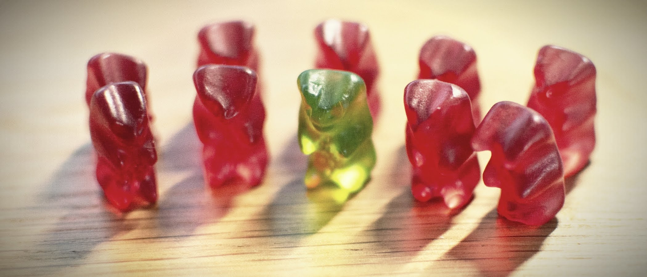 9 rote Gummibärchen und ein grüner stehen in 2 Reihen auf einem Tisch - zur Artikelseite Kontraste